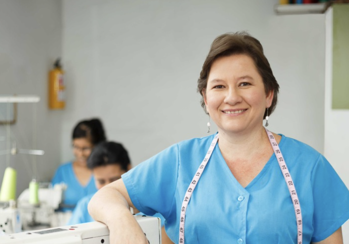 Mujer feliz frente a una maquina de coser